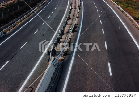 Aerial view of a paved highway road with white markings seen from above. Road repair, travel concept. Separating lanes on the road, a baffle for the safe movement of cars. Aerial view of a paved highway road with white markings seen from above. Road repair, travel concept. Separating lanes on the road, a baffle for the safe movement of cars. 119776937