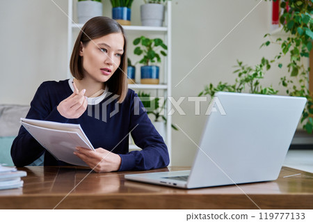 Young female college student studying using laptop computer for video chat 119777133