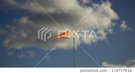 Red-white windsock against the blue sky, windy Red-white windsock against the blue sky, windy 119777616