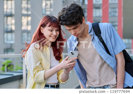 Friends young guy and girl college students talking looking at smartphone together, outdoor 119777694