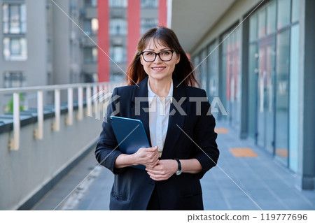 Mature confident business woman with digital tablet in black suit outdoors Mature confident business woman with digital tablet in black suit outdoors 119777696