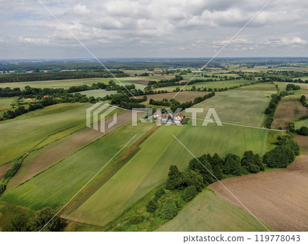 Aerial view of the dark, atmospheric sky over a small village among green fields 119778043