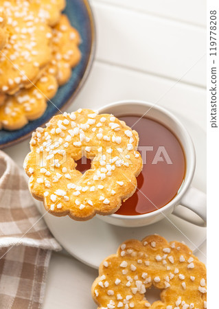 Sweet cookies in the shape of a flower. Tasty biscuits and cup of tea on white table. 119778208