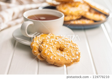 Sweet cookies in the shape of a flower. Tasty biscuits and cup of tea on white table. 119778210