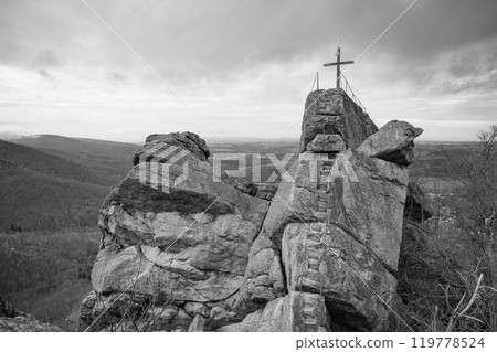 The Oresnik granite rock formation features a wooden summit cross, offering breathtaking views over the Jizera Mountains in Hejnice, Czechia. Black and white photography 119778524