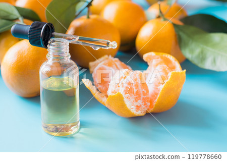 Essential oil of orange mandarin in glass bottle over pastel blue background. Spa and wellness concept. 119778660