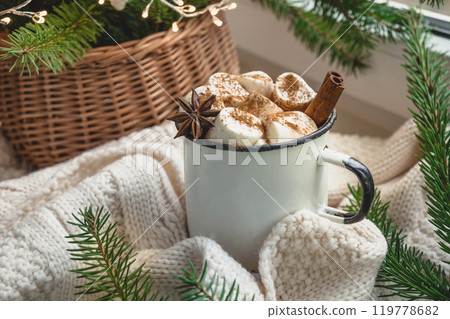 Winter warming mug of chocolate with marshmallow on windowsill with Christmas tree decor and garland. Christmas food. 119778682