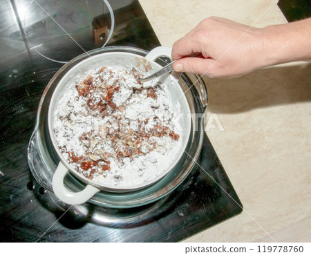 Powdered sugar, cocoa butter and grated cocoa in a container for making chocolate are heated in a water bath. Powdered sugar, cocoa butter and grated cocoa in a container for making chocolate are heated in a water bath. 119778760