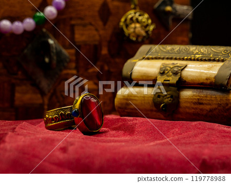 reproduction golden ring with ruby gem decorated medieval with an ivory casket on a red velvet table 119778988