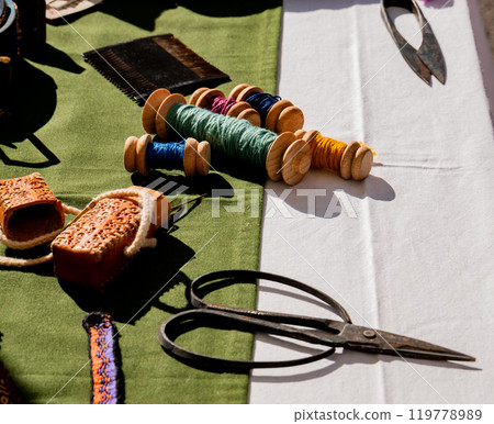 shot of ancient medieval sewing textile tools on a work table with bobbins and needles 119778989