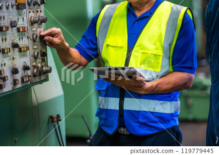 Man professional worker in heavy industry engineer wearing safety uniform at industrial. Male manager using tablet checking system construction manufacturing. 119779445