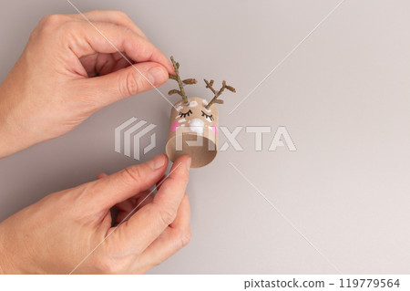 reindeer has small twigs attached to the top to represent antlers, white pom-pom representing the nose. creative and festive DIY project, perfect for holiday decoration or a fun craft activity 119779564