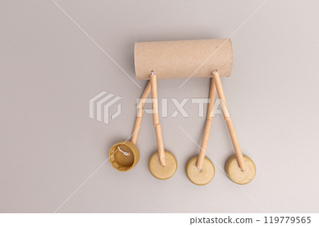Assembling DIY reindeer puppet leg with cardboard tube string bottle caps Close-up on neutral background for Christmas craft and recycling concept Tutorial shot showing process step, 119779565
