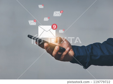 Hand-holding mobile phone with email icon on screen. Business communication technology concept. A human hand holds a phone while sending and receiving email from the internet. 119779722