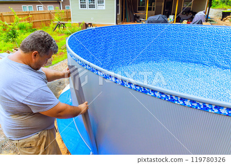 Worker is in process of installing metal frame of an above ground pool Worker is in process of installing metal frame of an above ground pool 119780326