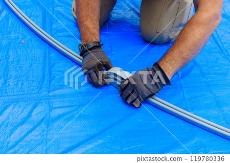 Worker assembling metal frame for an above ground swimming pool 119780336