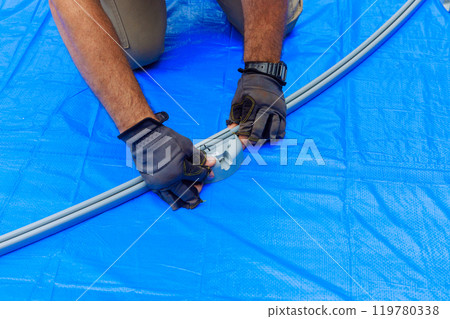 During assembly of metal frame for an above ground pool, worker is working During assembly of metal frame for an above ground pool, worker is working 119780338