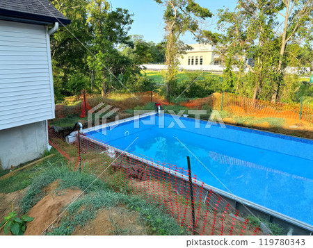 Installation of swimming pool construction at ground near house in back yard 119780343