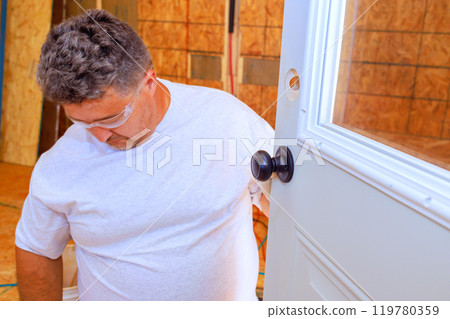 Lock doorknob installed by professional locksmith using screwdriver on an entrance door to house 119780359