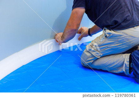 Pool liners are protected by durable foam construction installed by worker in ground pool 119780361