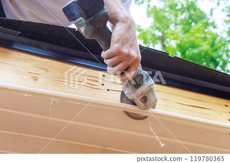 Cutting off established vinyl soffit panels facade ceiling of new house to a given size Cutting off established vinyl soffit panels facade ceiling of new house to a given size 119780365
