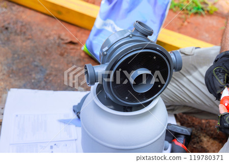 Worker installing sand filter system tank equipment for cleaning swimming pools 119780371