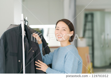 Woman putting clothes on a hanger Woman putting clothes on a hanger 119781012