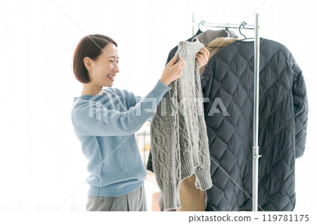 Woman putting clothes on a hanger 119781175