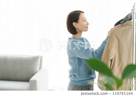 女人把衣服掛在衣架上 119781184