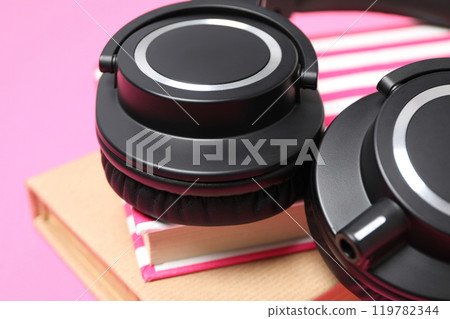Books with modern headphones, on a pink background. 119782344