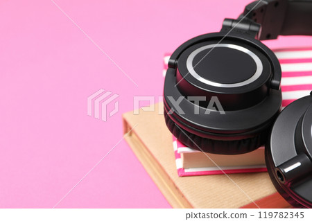Books with modern headphones, on a pink background. 119782345