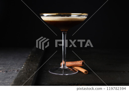 Martini espresso cocktail in glass and cinnamon sticks on dark background 119782394