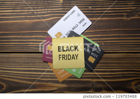 Top view of notes with Black Friday text on stack of debit or credit card on wooden background Top view of notes with Black Friday text on stack of debit or credit card on wooden background 119783488