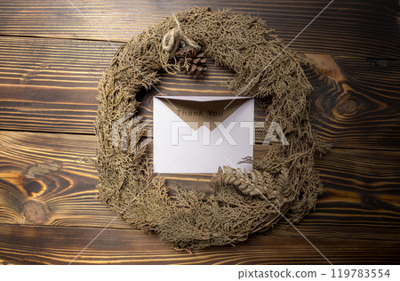 Top view of envelope and postcard with brown card with words Thank You written on it and wreath Top view of envelope and postcard with brown card with words Thank You written on it and wreath 119783554