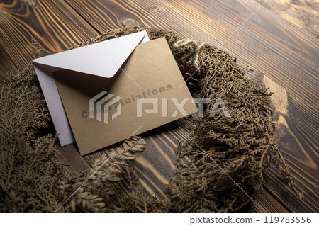 Envelope and postcard with brown card with words Congratulations on it with wreath Envelope and postcard with brown card with words Congratulations on it with wreath 119783556