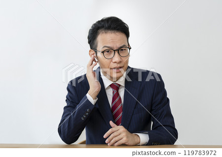 A businessman in his 40s looking at the camera with earphones on A businessman in his 40s looking at the camera with earphones on 119783972