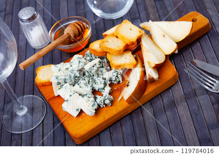 Blue cheese served on wooden board with pear, bread and honey 119784016
