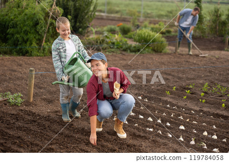 Woman planting seeds boy watering beds Woman planting seeds boy watering beds 119784058