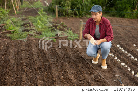 Young woman planting seeds in field 119784059