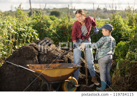 Young woman and boy putting soil in wheelbarrow Young woman and boy putting soil in wheelbarrow 119784115