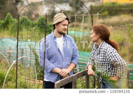Female farmer friendly talking to her male neighbour on backyard on day 119784135