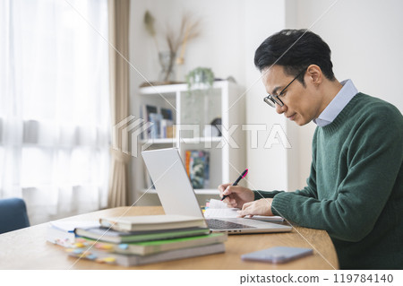 A man in his late 30s working at a desk A man in his late 30s working at a desk 119784140