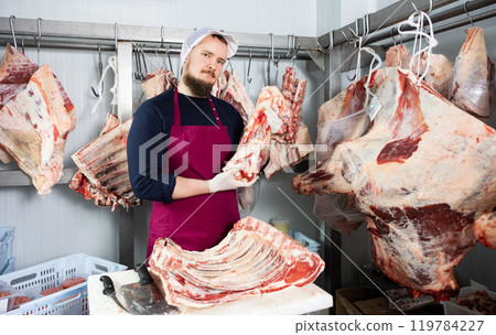 Bearded butchery worker preparing fresh veal cuts for sale Bearded butchery worker preparing fresh veal cuts for sale 119784227