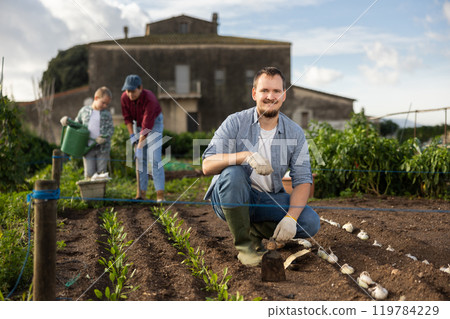 Young man with hoe in field of harvest Young man with hoe in field of harvest 119784229