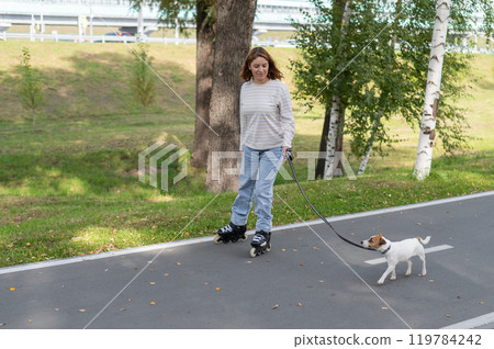 Caucasian woman roller skating with her jack russell terrier dog in park.  119784242