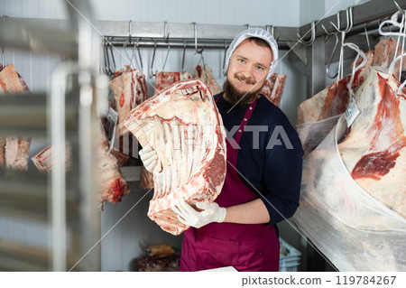 Male butcher shop butcher shows raw chopped carcasses and ribs 119784267