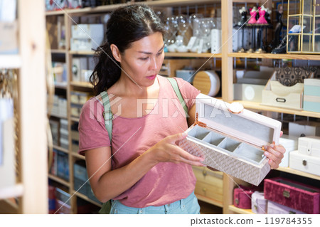 Female shopper selects wooden jewelry boxes at hardware supermarket Female shopper selects wooden jewelry boxes at hardware supermarket 119784355