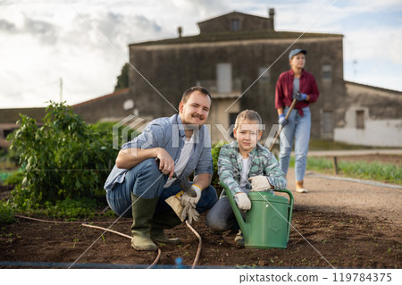Man and his son planting seeds on a farm 119784375