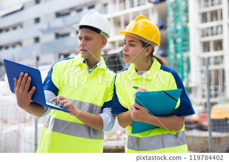 Two architects with laptop discussing construction plan Two architects with laptop discussing construction plan 119784402