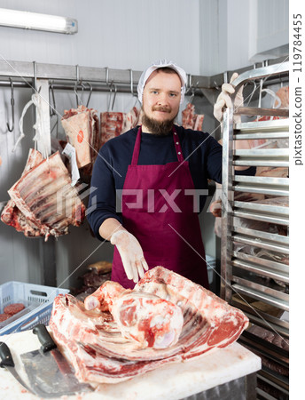 Male butcher shop butcher shows raw chopped carcasses and ribs 119784455